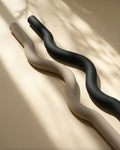 Muna Long Dumbbell Beam in sleek design, showcasing the black and beige colors on a textured background.