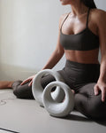 Woman in activewear using kettlebell and exercise wheels during a Pilates session on a yoga mat.