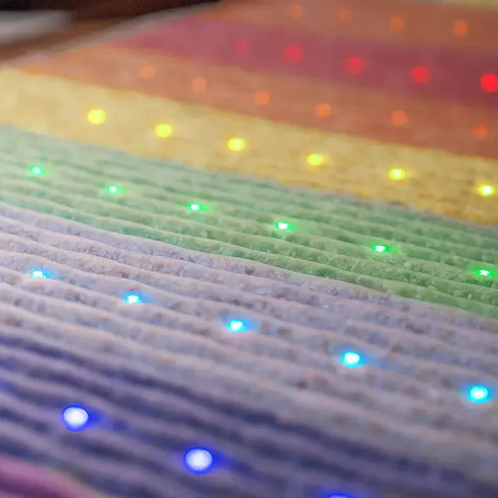 Close-up of the Rainbow Chakra PEMF Far Infrared Heating Mat displaying colorful light patterns.