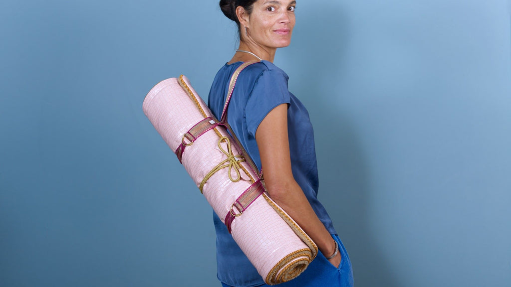 Woman carrying a Holistic Silk Yoga Rug Mat, showcasing its luxury design and functionality for yoga enthusiasts.