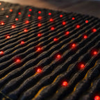 PEMF Far Infrared Heating Mat close-up showing red light therapy points on the textured surface.