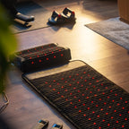 PEMF Far Infrared Heating Mat placed on wooden floor with accessories in a cozy room.