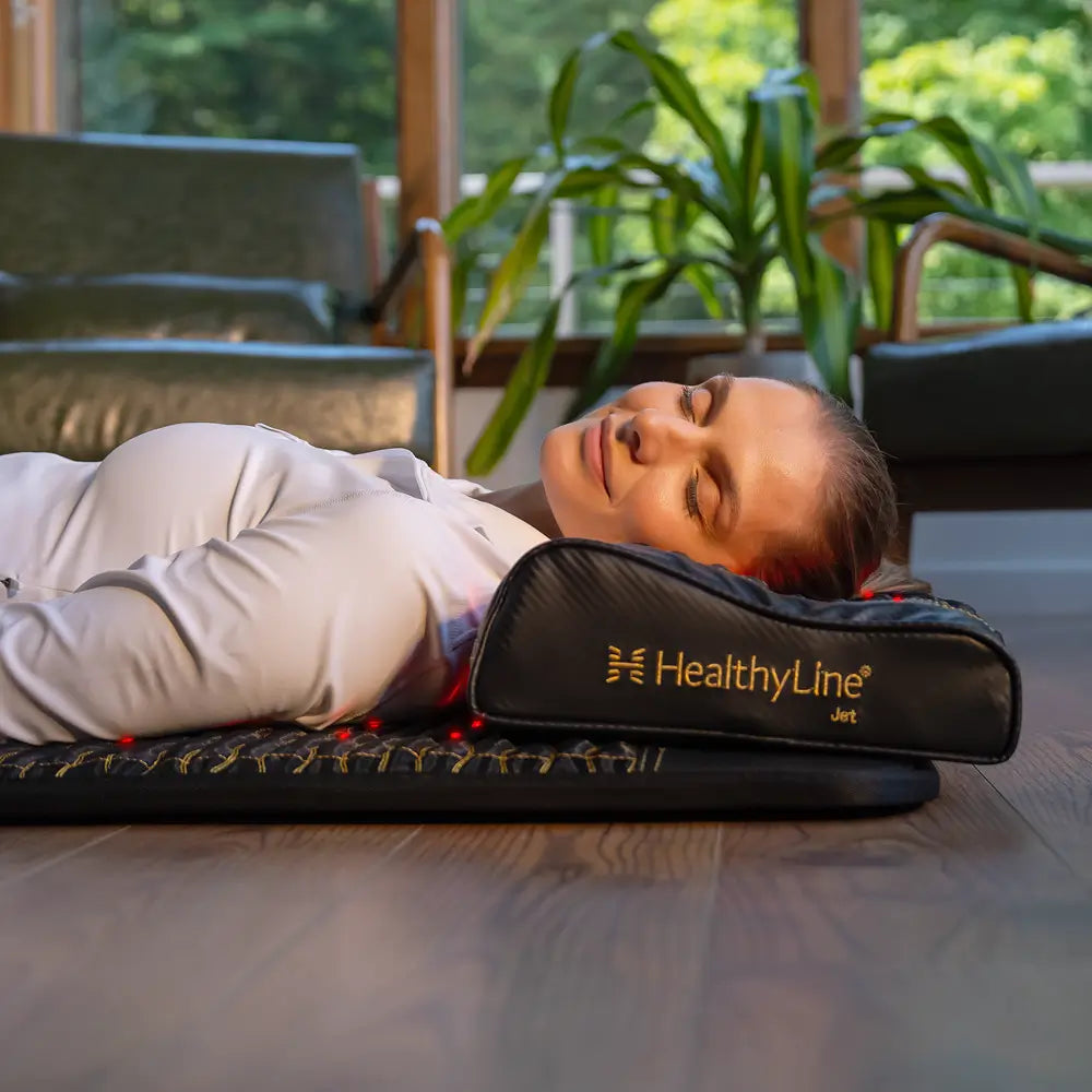 A woman relaxing on the HealthyLine Infrared Pillow, enjoying the benefits of far infrared heat and red light therapy.