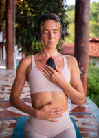 Woman practicing mindfulness with Sensate vagus nerve toning device for stress relief.