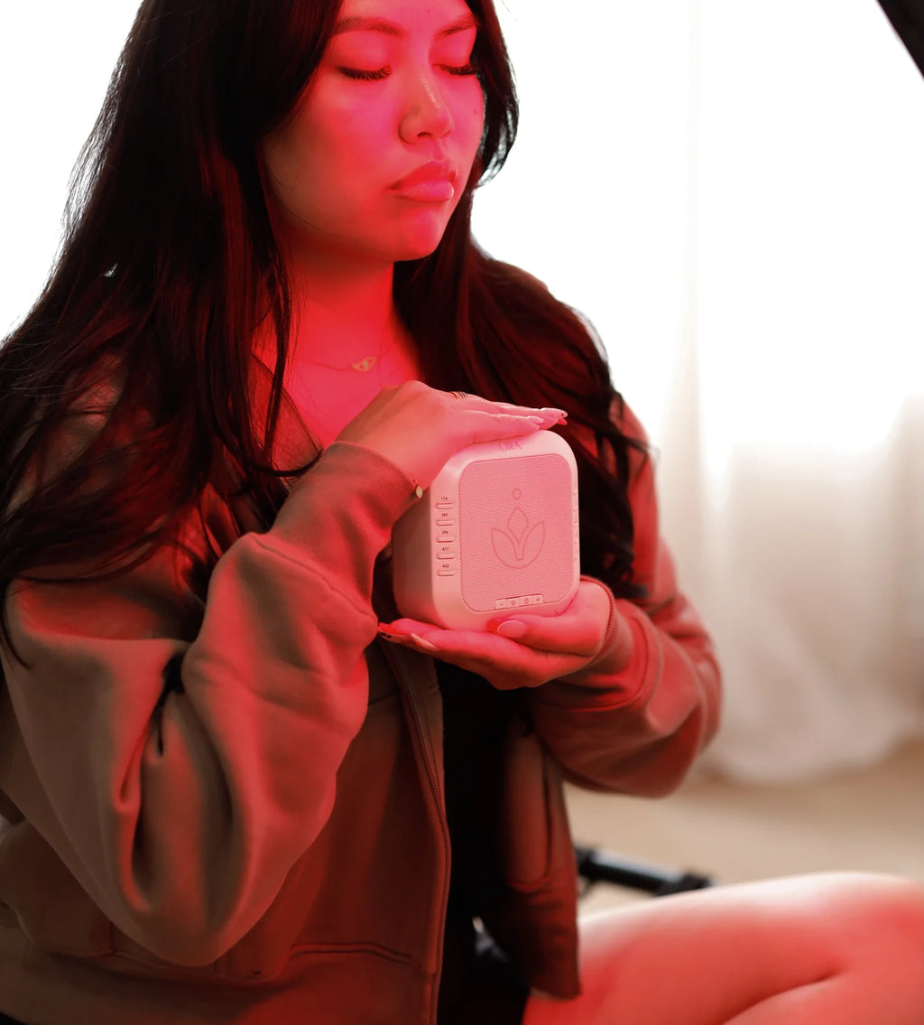 Person using the ORA sound frequency machine for relaxation and meditation in a serene environment.