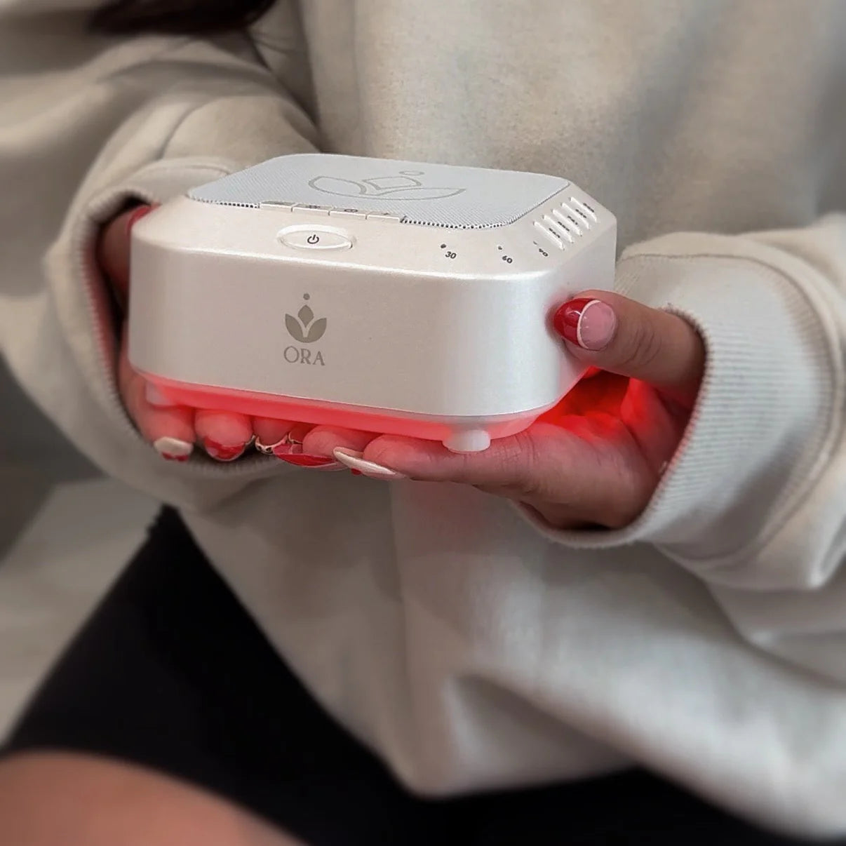 ORA Sound Frequency Machine in a person's hands, designed for calming sound therapy and enhancing meditation.
