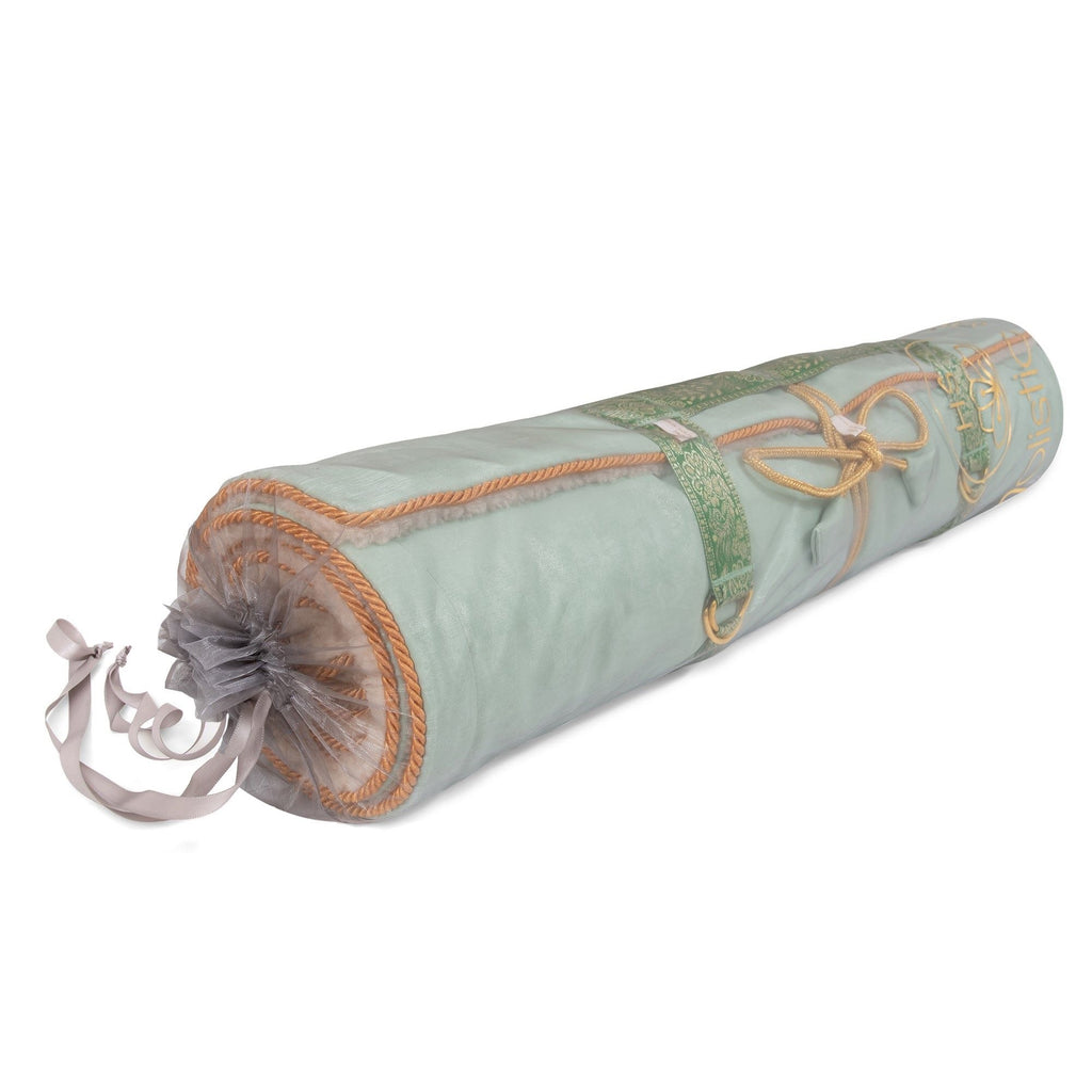 Holistic Silk luxury yoga rug mat rolled up with a decorative ribbon and plush fabric in soft colors.
