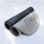 Muna oval yoga mat in black and gray colors, showcasing a comfortable design for various movement practices.