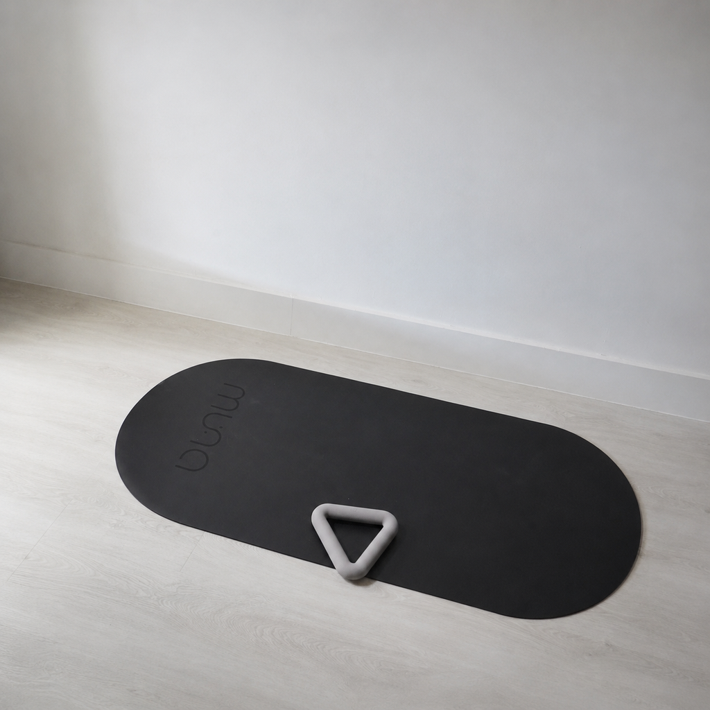 Muna oval yoga mat in a minimalistic setting with a gray yoga prop on it, designed for comfort and stability during workouts.
