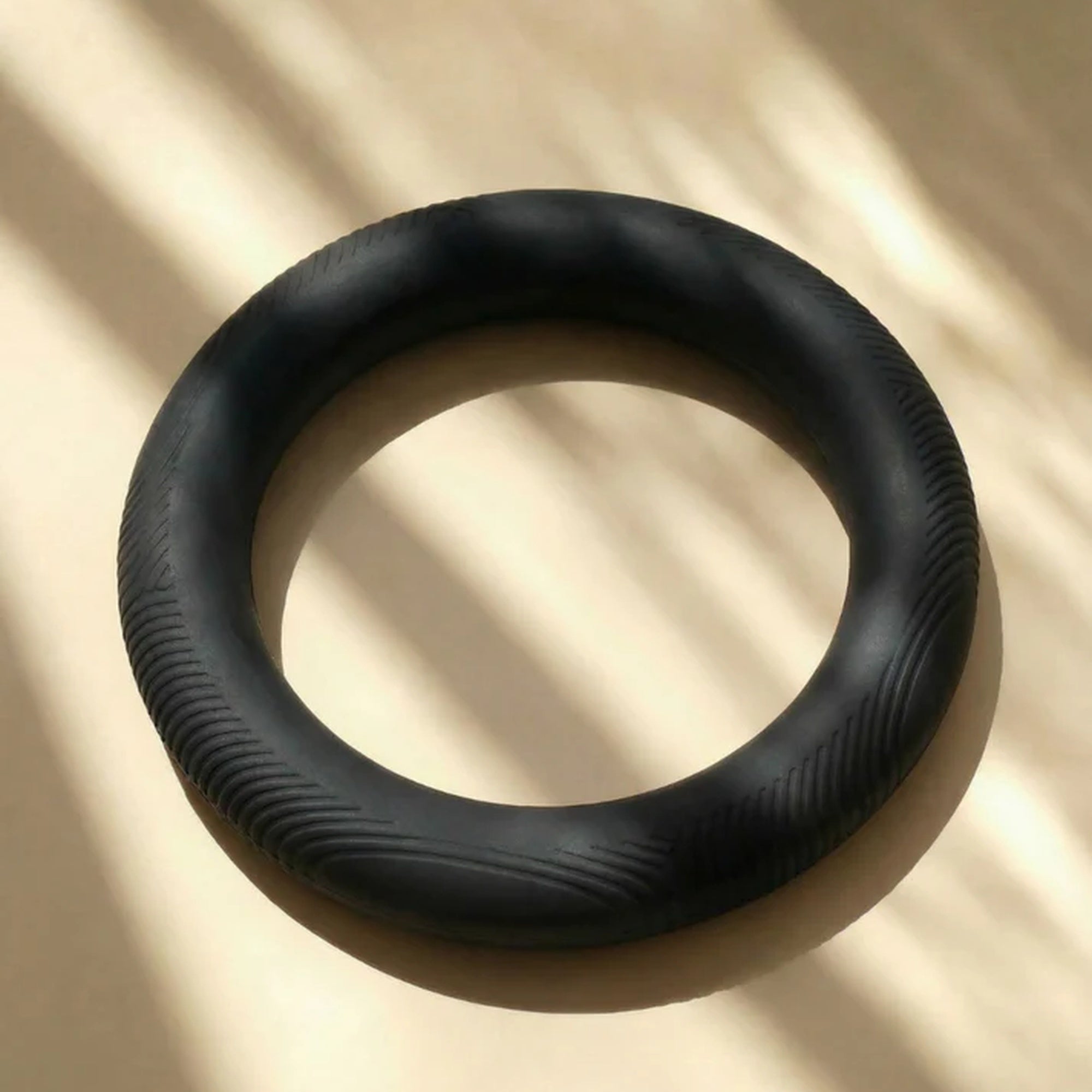MUNA Dumbbell Ring shown on a light surface, featuring a smooth silicone coating for optimal grip and multiple hand positions.