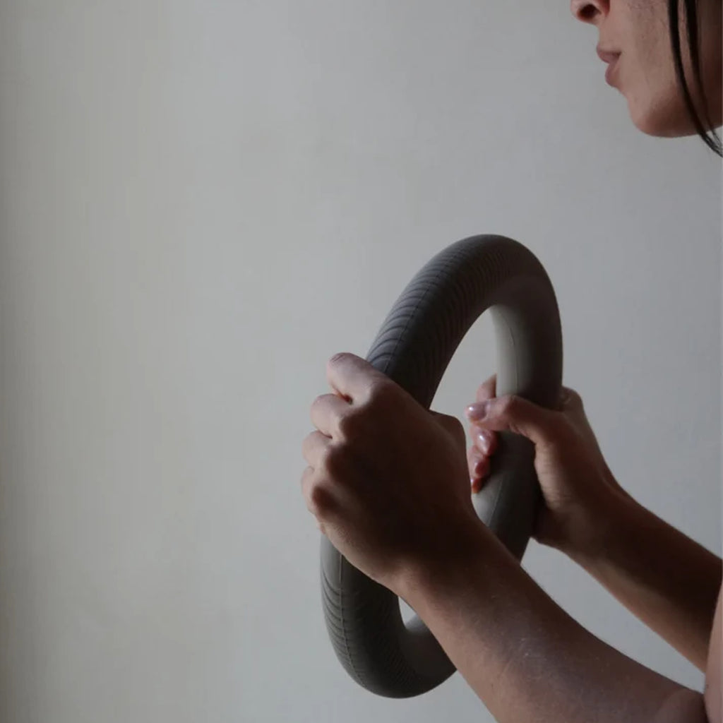 Close-up of hands gripping the MUNA Dumbbell Ring, showcasing its unique design and silicone coating.