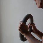 Close-up of hands gripping the MUNA Dumbbell Ring, showcasing its unique design and silicone coating.