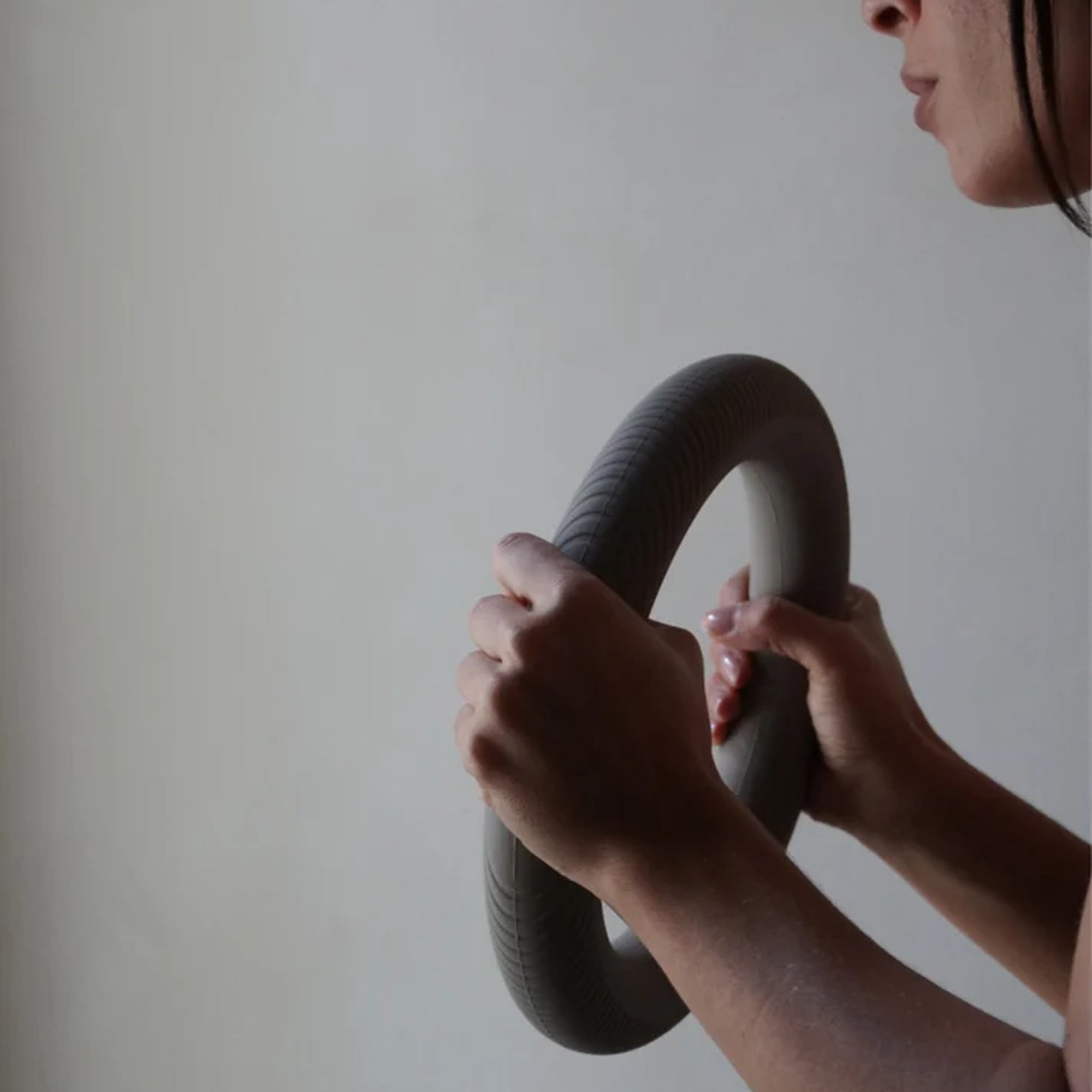 Close-up of hands gripping the MUNA Dumbbell Ring, showcasing its unique design and silicone coating.